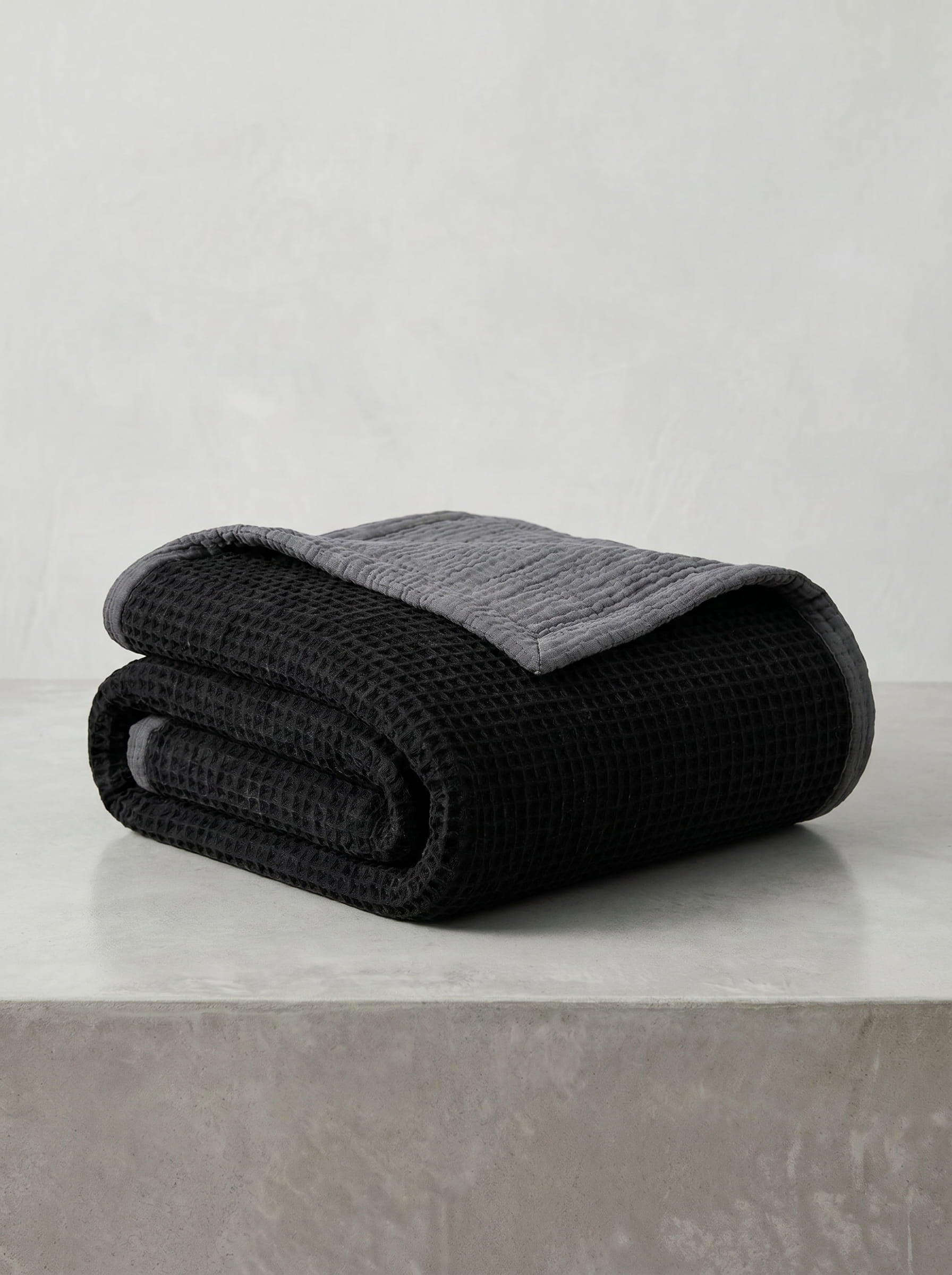 Creative Home's Black waffle weave organic cotton blanket with soft muslin backing styled on rustic wooden bench near fireplace, luxury reversible throw,BB-DesH-WaMusBlnkt-Bla-6070,BB-DesH-WaMusBlnkt-Bla-Tw,BB-DesH-WaMusBlnkt-Bla-Q,BB-DesH-WaMusBlnkt-Bla-K,BB-DesH-WaMusBlnkt-Bla-100118,BB-DesH-WaMusBlnkt-Bla-100125